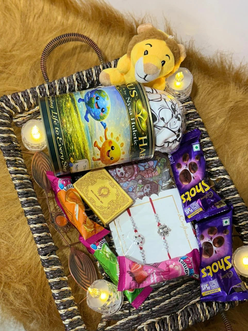 Complete Classic Rakhi Gift Hamper with Sun Activated Colour-Changing Kids T-Shirt, Evil Eye Crown Rakhi, chocolates, colourful lollipops, and Roli Chawal set.