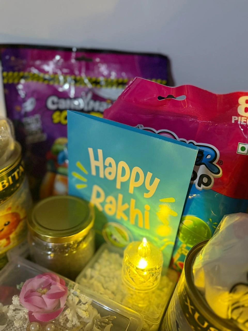 Happy Rakhi greeting card with festive gifts inside the Raksha Bandhan hamper.