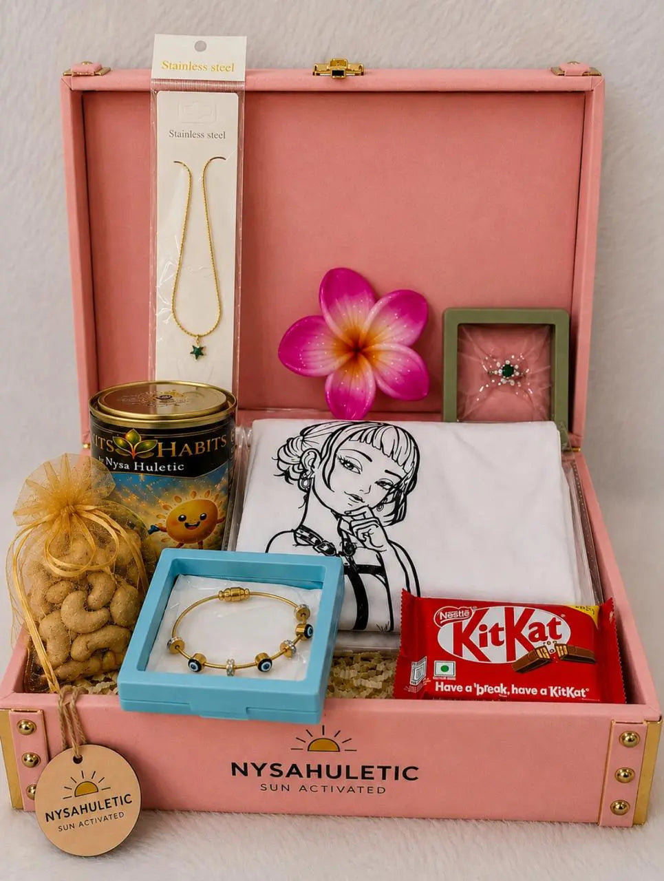Open premium Rakhi keepsake gift box featuring Sun Activated Kids T-Shirt, Evil Eye bracelet, necklace, ring, KitKat, cashew nuts, and festive accessories.