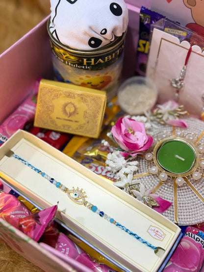 Close-up of Raksha Bandhan gift box contents including Evil Eye Rakhi, decorative diya, chocolates, and festive essentials.