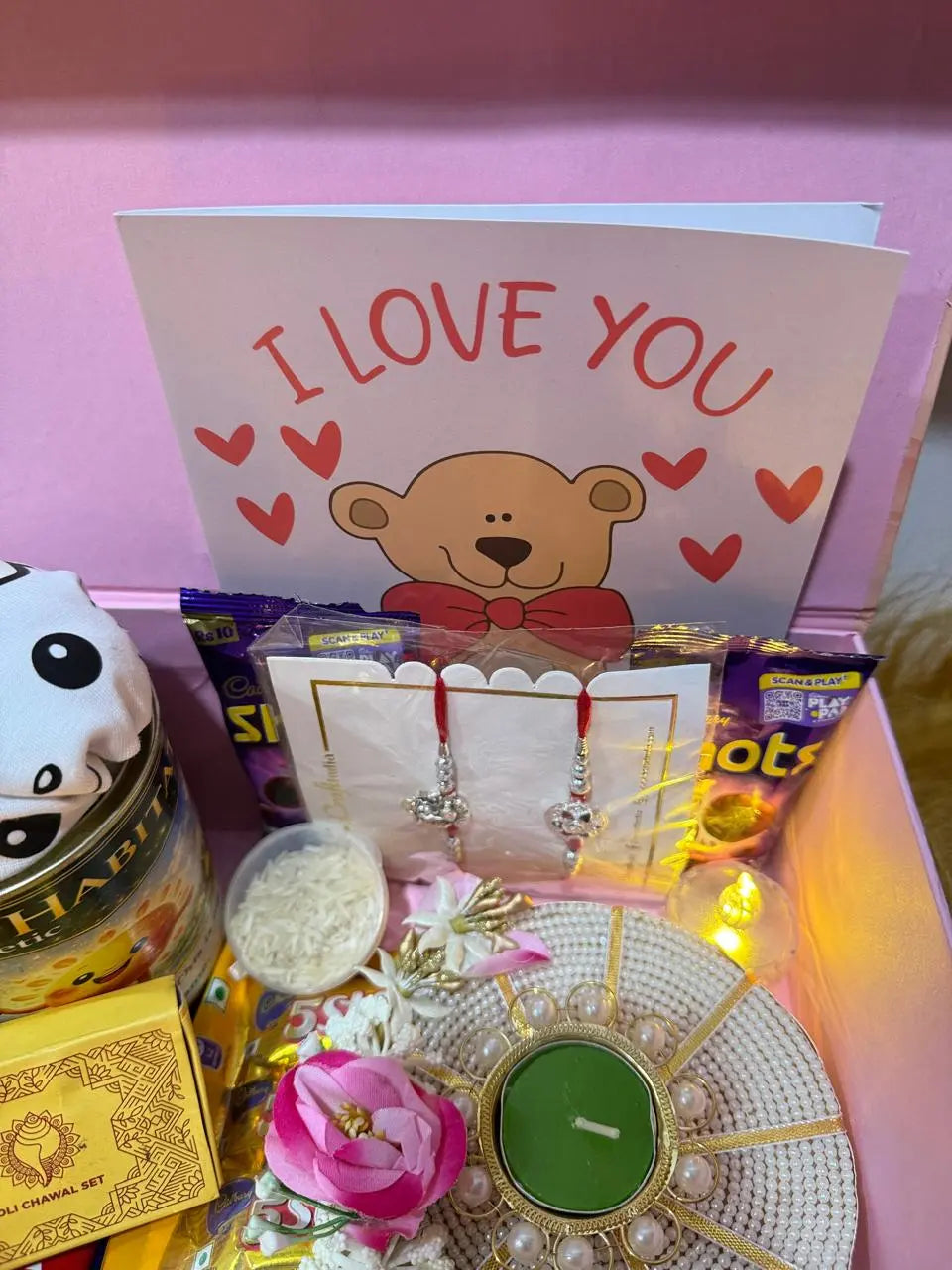 Open Raksha Bandhan gift box with Sun Activated Colour-Changing Kids T-Shirt, Rakhi, chocolates, greeting card, diya, and festive accessories.